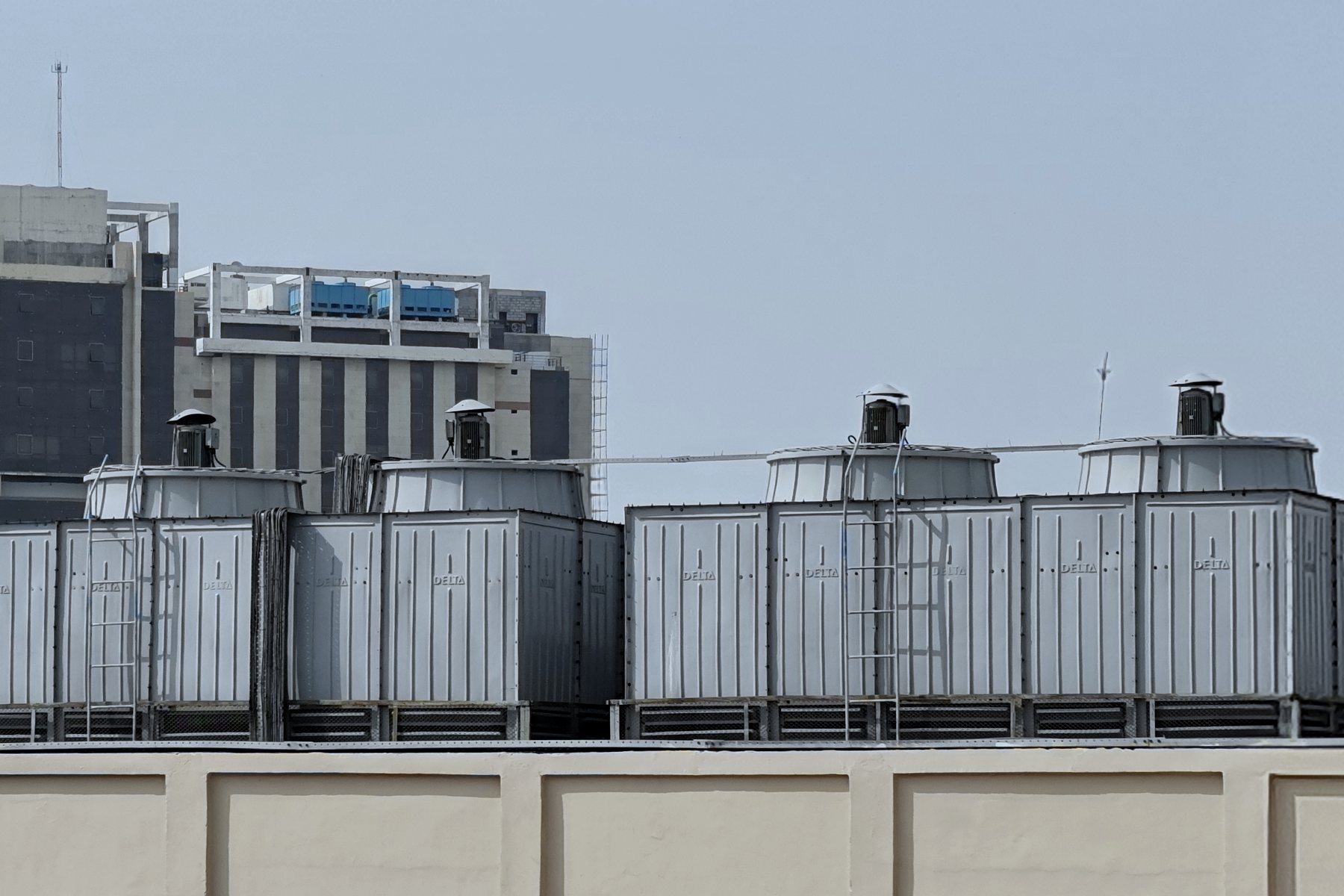 A bank of induced-draft cooling towers on a building roof, with fan cowls, louvred sides and access ladders.